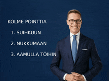 a man in a suit and tie is standing in front of a blue background with kolme pointtia written on it