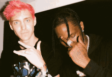 a man with pink hair is standing next to another man with braids