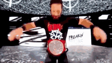 a man in a black shirt is holding a red wrestling belt .