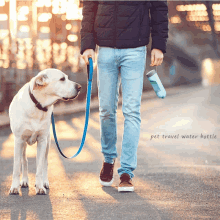 a man is walking a dog on a leash with a pet travel water bottle