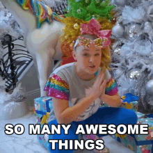 a girl with a unicorn on her head is kneeling in front of a christmas tree with the words " so many awesome things " below her