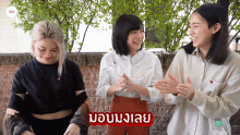 three women are clapping their hands in front of a brick wall and a sign that says " i love "