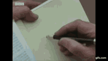 a close up of a person holding a pen and writing on a piece of paper .