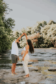 a man and a pregnant woman are dancing in the water