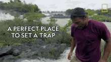 a man in a purple shirt stands in front of a waterfall with the words " a perfect place to set a trap " below him