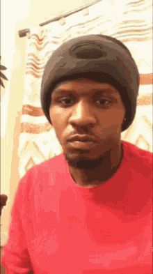 a man wearing a red shirt and a black beanie looks at the camera