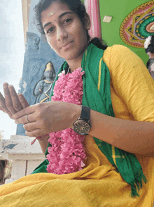 a woman wearing a watch and a green scarf holds her hands up