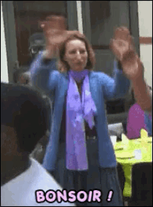 a woman in a blue jacket and purple scarf is standing in front of a sign that says bonsoir !