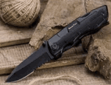 a black pocket knife is sitting on top of a wooden table next to a ball of twine .