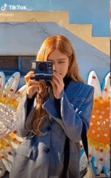 a woman is taking a picture with a camera in front of a flower sculpture .