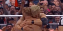 a couple of men hugging each other in a wrestling ring .