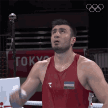 a boxer wearing a red tank top with the letter t on it stands in front of a tokyo sign