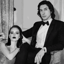 a man in a tuxedo sits next to a woman