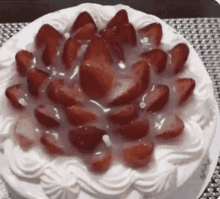 a cake with whipped cream and strawberries on top is on a plate on a table .