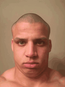 a man with a shaved head looks at the camera with a serious look on his face