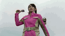 a woman in a pink jacket is holding a cellphone