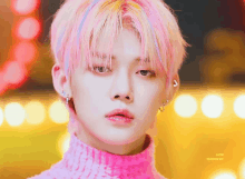 a close up of a person wearing a pink sweater and earrings