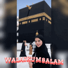 a woman in a hijab stands in front of a kaaba with the words " selamat " on the bottom