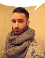 a man wearing a scarf around his neck has a speech bubble above him