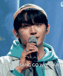 a young man is singing into a microphone with the words go wonsang go wonsang written below him