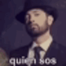 a man with a beard wearing a hat and a suit .