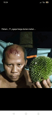 a man with a bloody head is holding a durian in front of his face