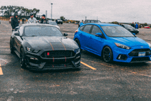 a black ford mustang and a blue ford focus are parked next to each other in a parking lot