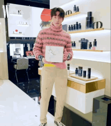 a man in a pink sweater is holding a gift box in front of a display of dior products