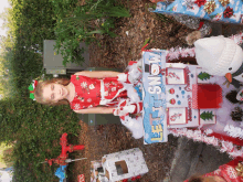 a little girl in a red dress is standing next to a sign that says let it snow