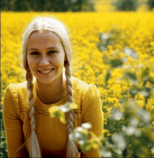 a woman in a field of yellow flowers smiles for the camera