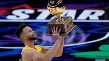 basketball player holding a trophy in front of a star logo