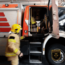 a man in a yellow helmet stands next to a fire truck with a sticker on the tire that says pelastuslaitos