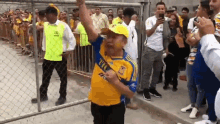 a man wearing a yellow shirt with the word tigres on it is dancing in front of a crowd of people .