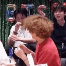 a group of young men are sitting in front of a green curtain eating hamburgers .