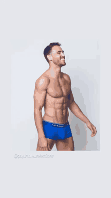 a shirtless man is wearing blue boxer shorts with the word clubbing written on the waistband