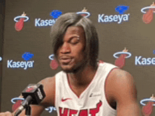 a man in a heat jersey is talking into a microphone .