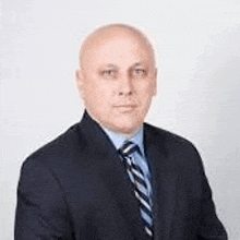 a man in a suit and tie is sitting in front of a white background .