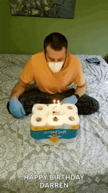 a man wearing a mask and gloves is sitting on a bed with a birthday cake made out of toilet paper