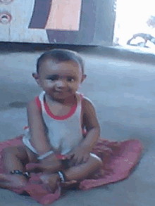 a baby is sitting on a pink blanket on the floor