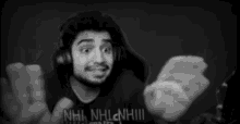 a man wearing headphones is making a funny face while waving his hand in a black and white photo .