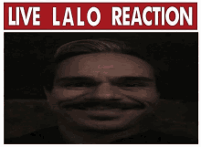 a man with a mustache is smiling in front of a live lalo reaction sign