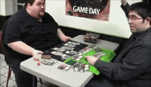 two men are playing a board game at a table .