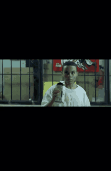 a boy drinking from a cup in front of a sign that says coca cola