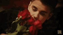 a person holding a bunch of red roses with snl written on the bottom right