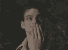 a man is covering his mouth with his hand in a blurry photo .