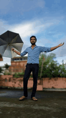 a man in a blue shirt is holding a black umbrella