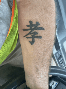 a man 's arm has a chinese symbol tattoo on it