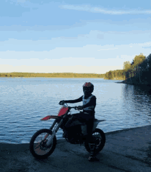 a man is riding a dirt bike on a beach next to a lake .