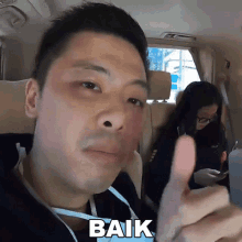 a man in a car giving a thumbs up with the word baik written below him