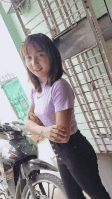 a girl in a purple nike shirt is standing next to a motorcycle